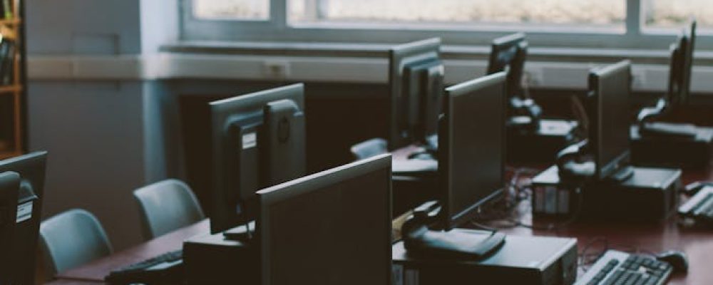 Spacious computer lab with rows of monitors and keyboards in a sunlit room.